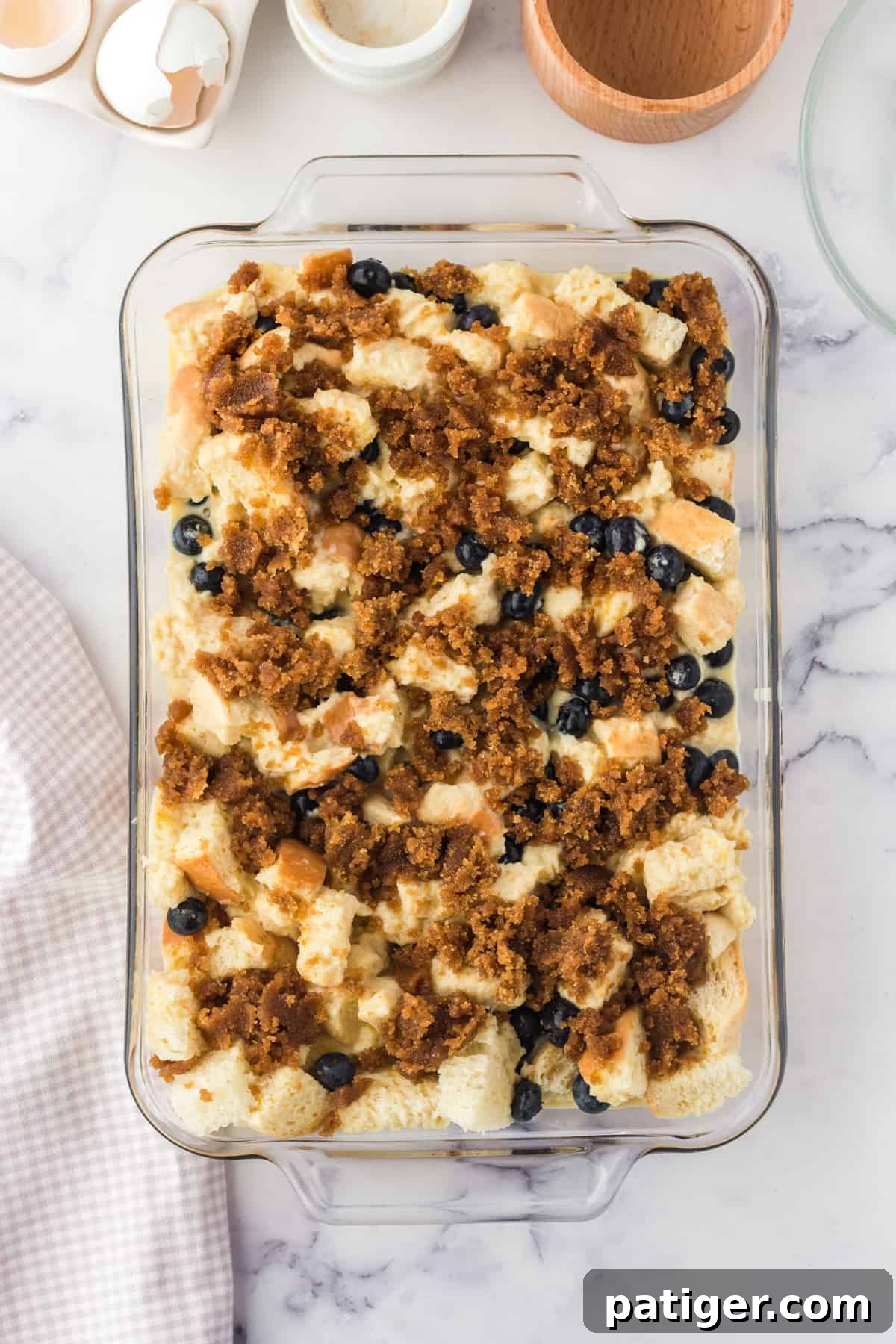 An unbaked blueberry French toast casserole with a generous topping of cinnamon sugar, ready for the oven.