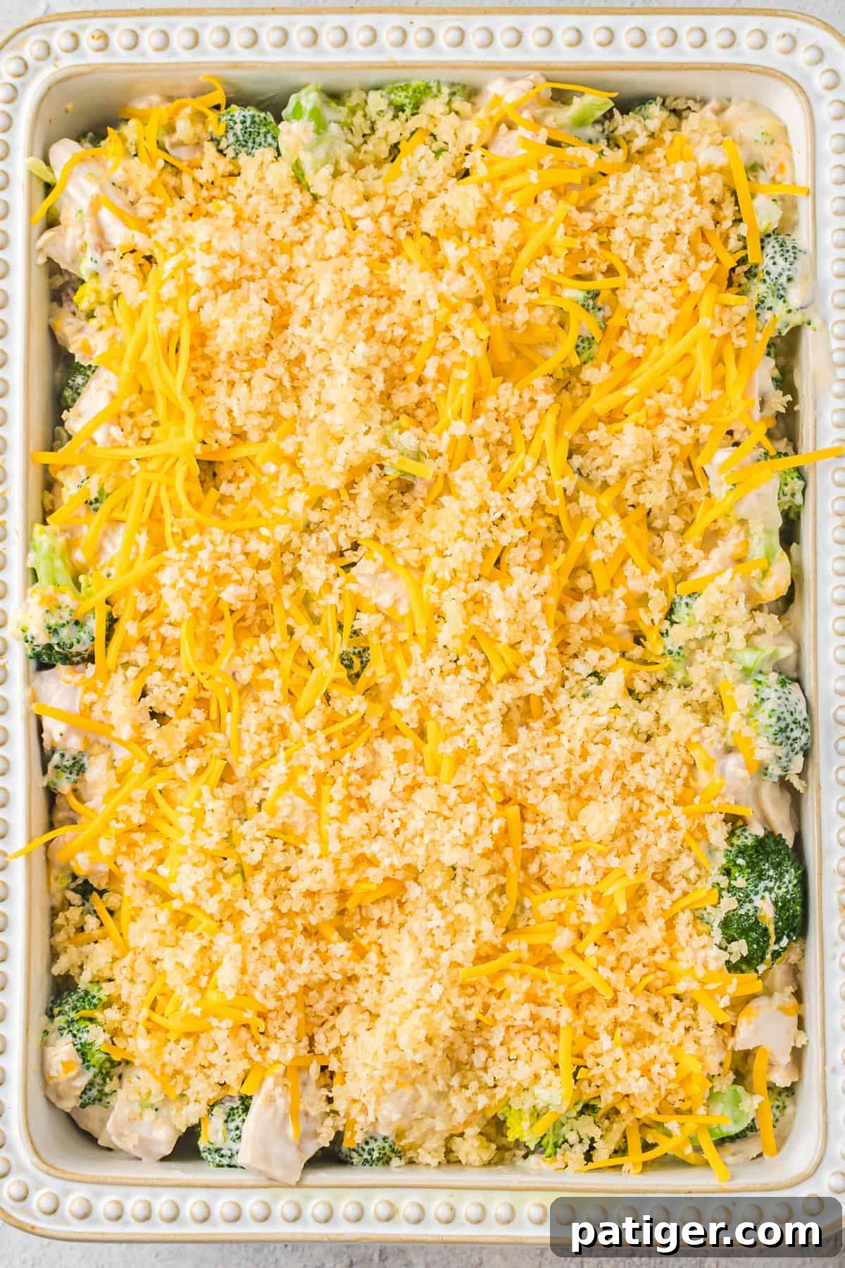 Chicken Divan topped with shredded cheese and panko breadcrumbs before baking.