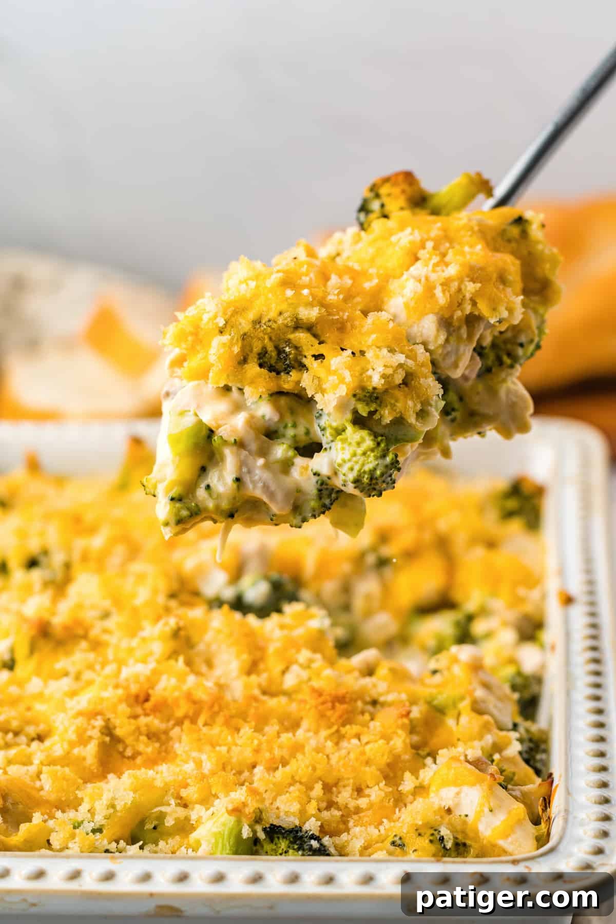 Serving spoon lifting a serving of chicken divan out of casserole dish.