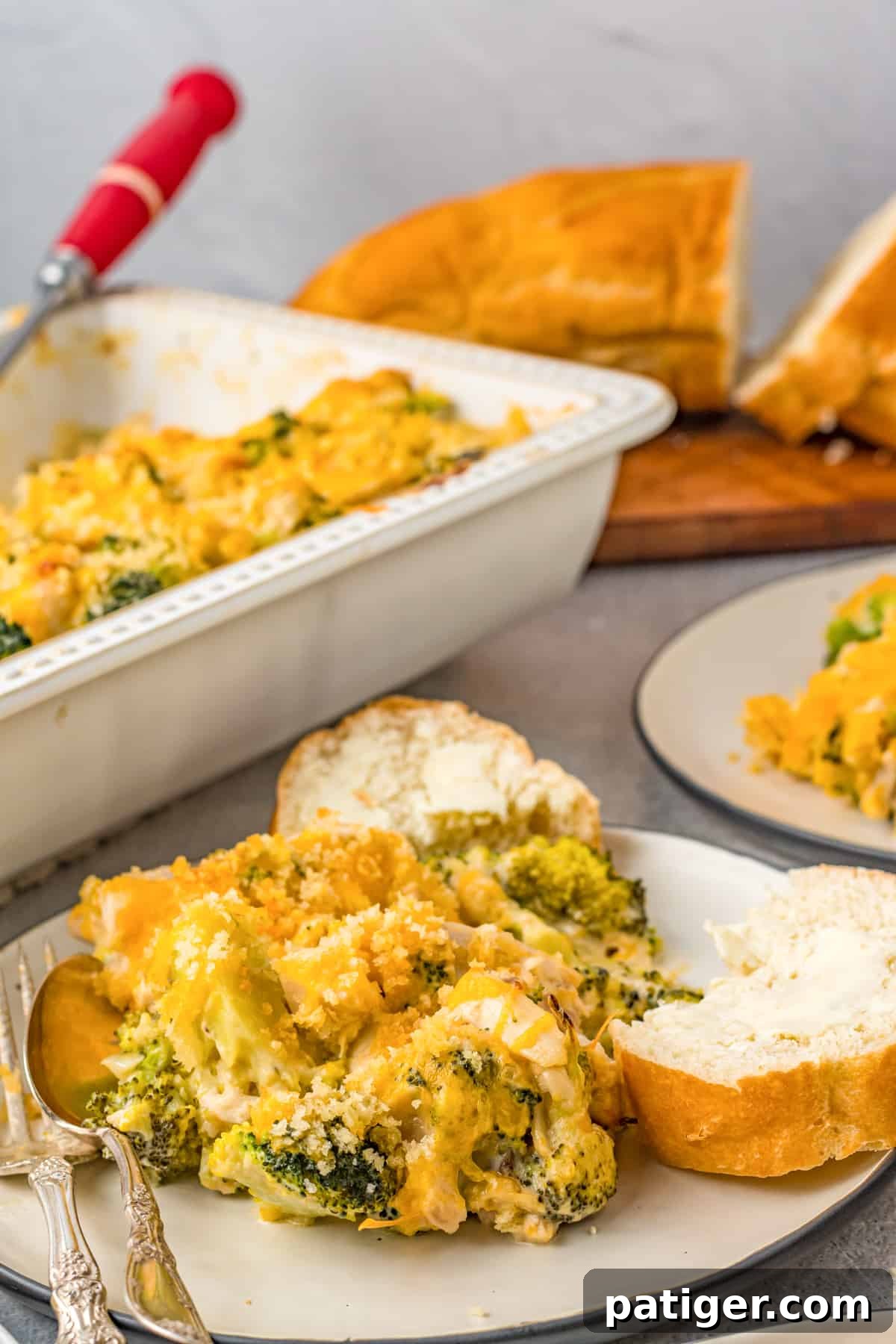 Chicken Divan Casserole served with bread, with additional casserole and bread behind it.