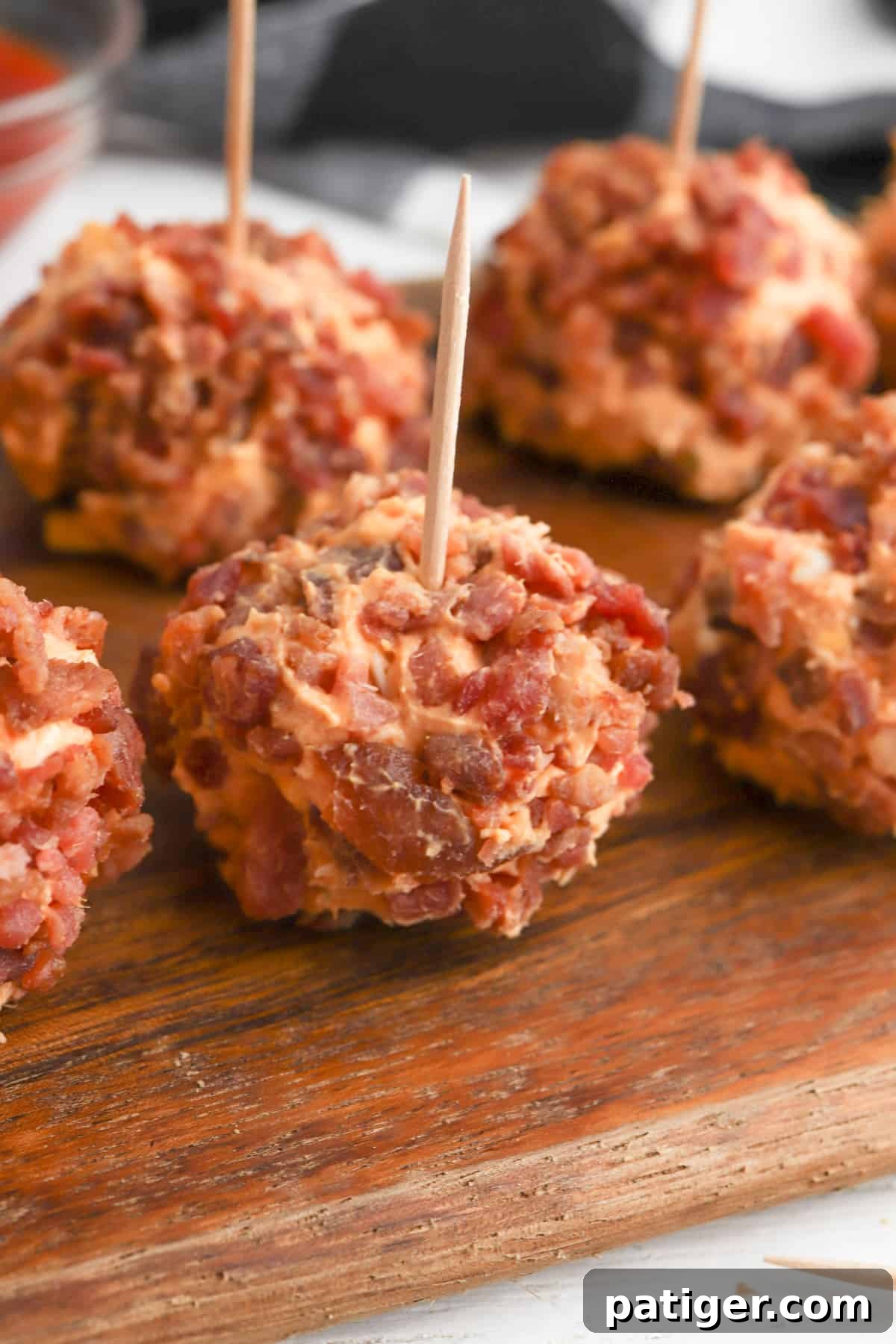 Mini Buffalo Chicken Cheese Balls served on toothpicks on a wooden cutting board, surrounded by fresh herbs.