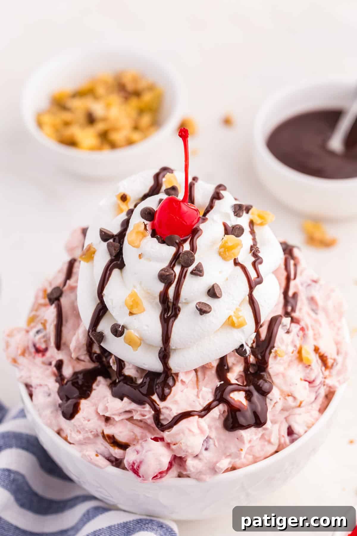 Banana split fluff dessert is a white bowl topped with sundae toppings.
