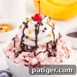 Banana split fluff dessert is a white bowl topped with sundae toppings.