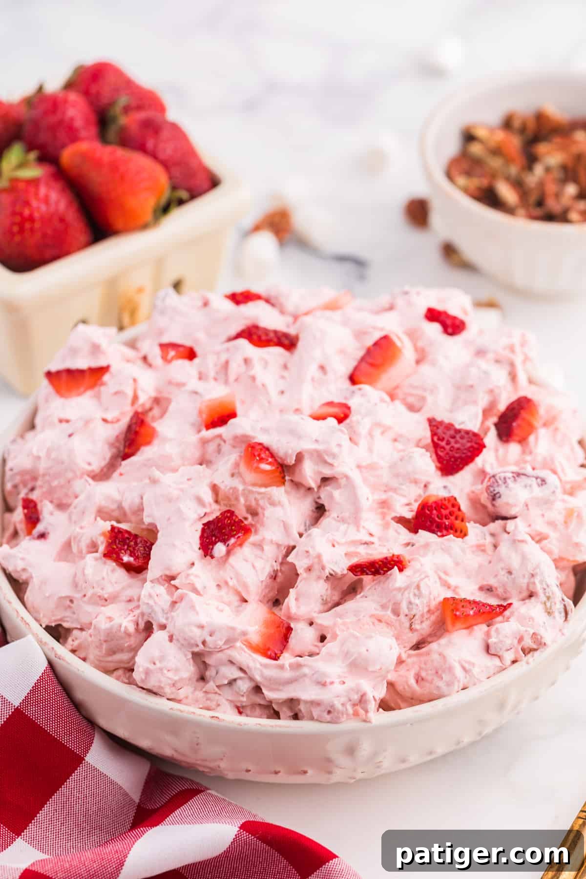 Strawberry Cloud Salad 2 Strawberry Fluff Dessert Salad with fresh strawberries and pecans in the background.