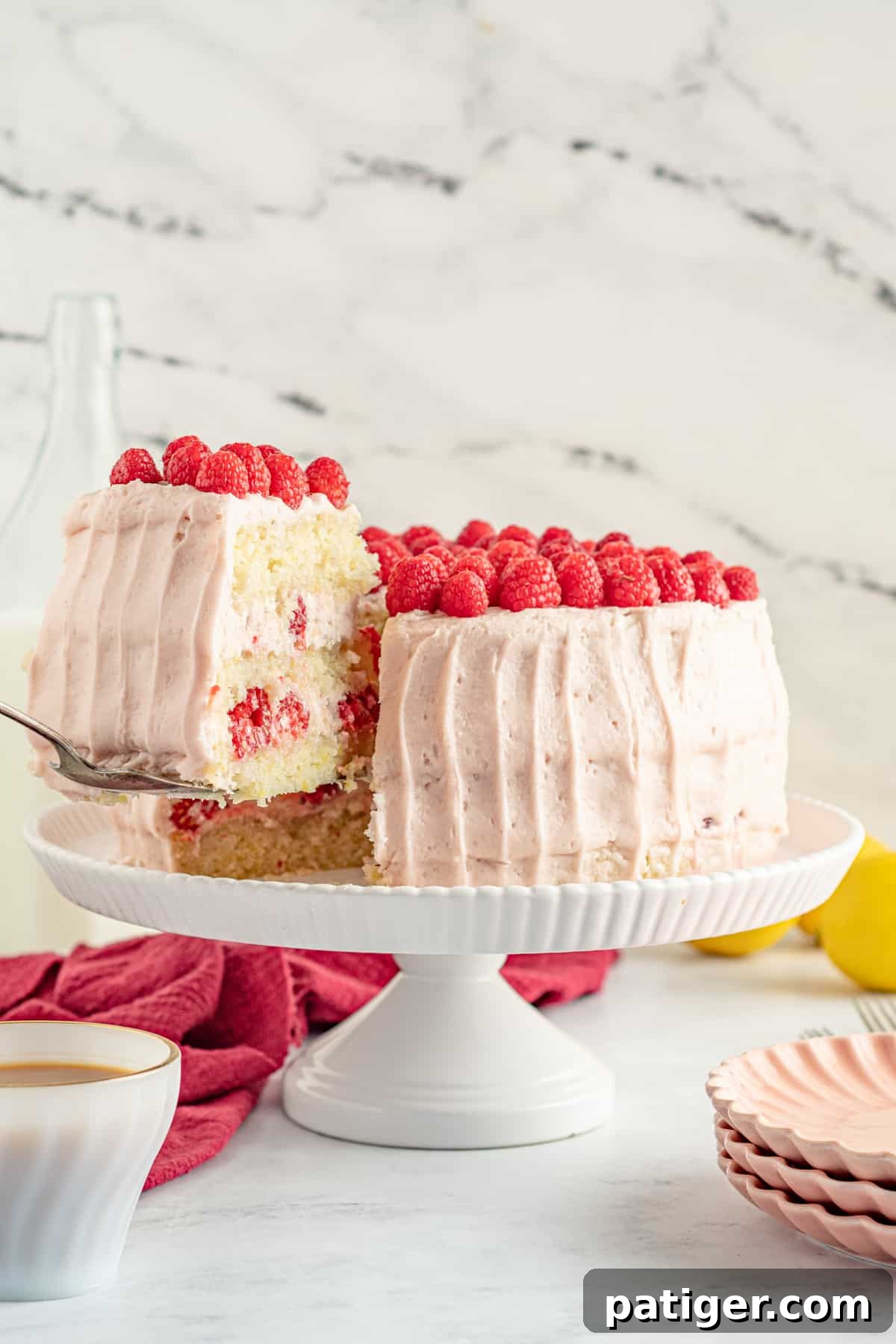 Slice of cake being lifted from the lemon and raspberry layer cake, showcasing the beautiful layers.