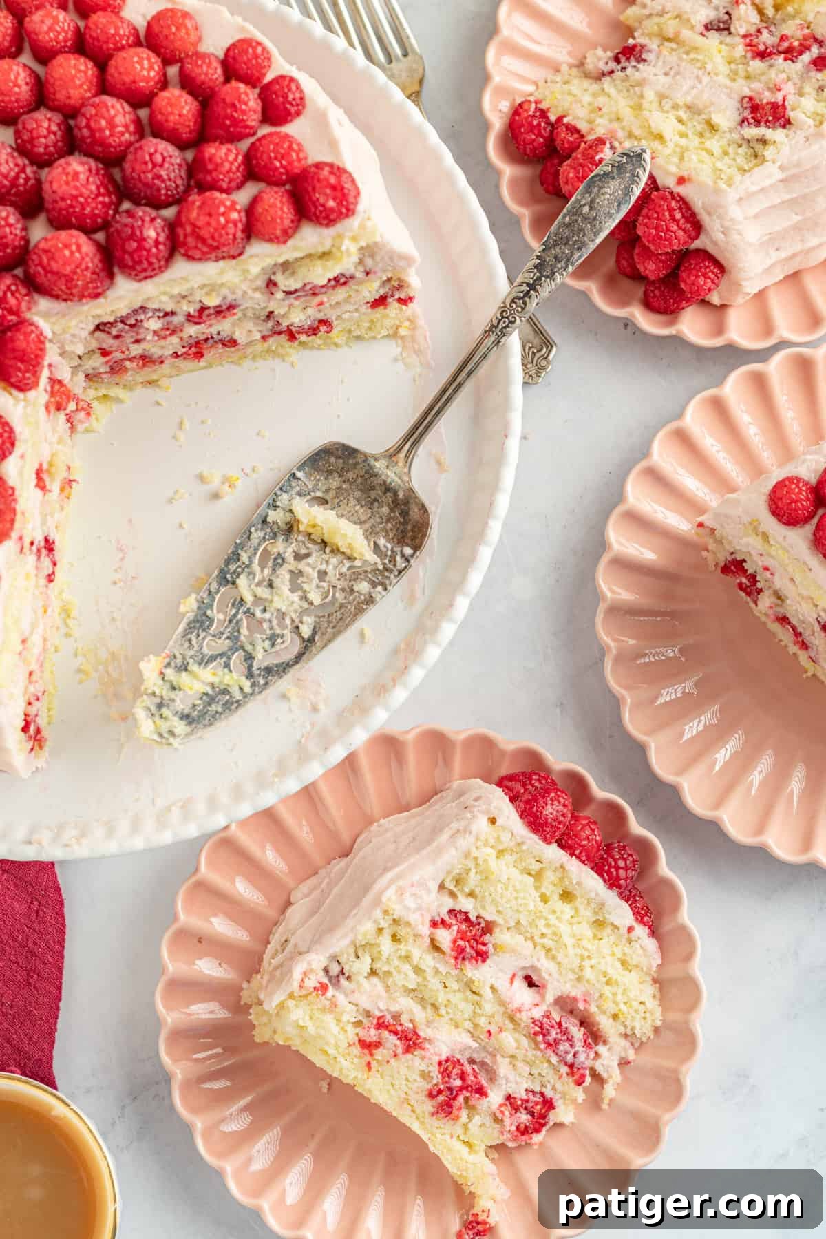 Slices of raspberry lemon cake on individual plates, with the remaining layer cake in the background.