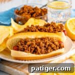 Hot dogs topped with homemade chili sauce on a plate with potato chips.