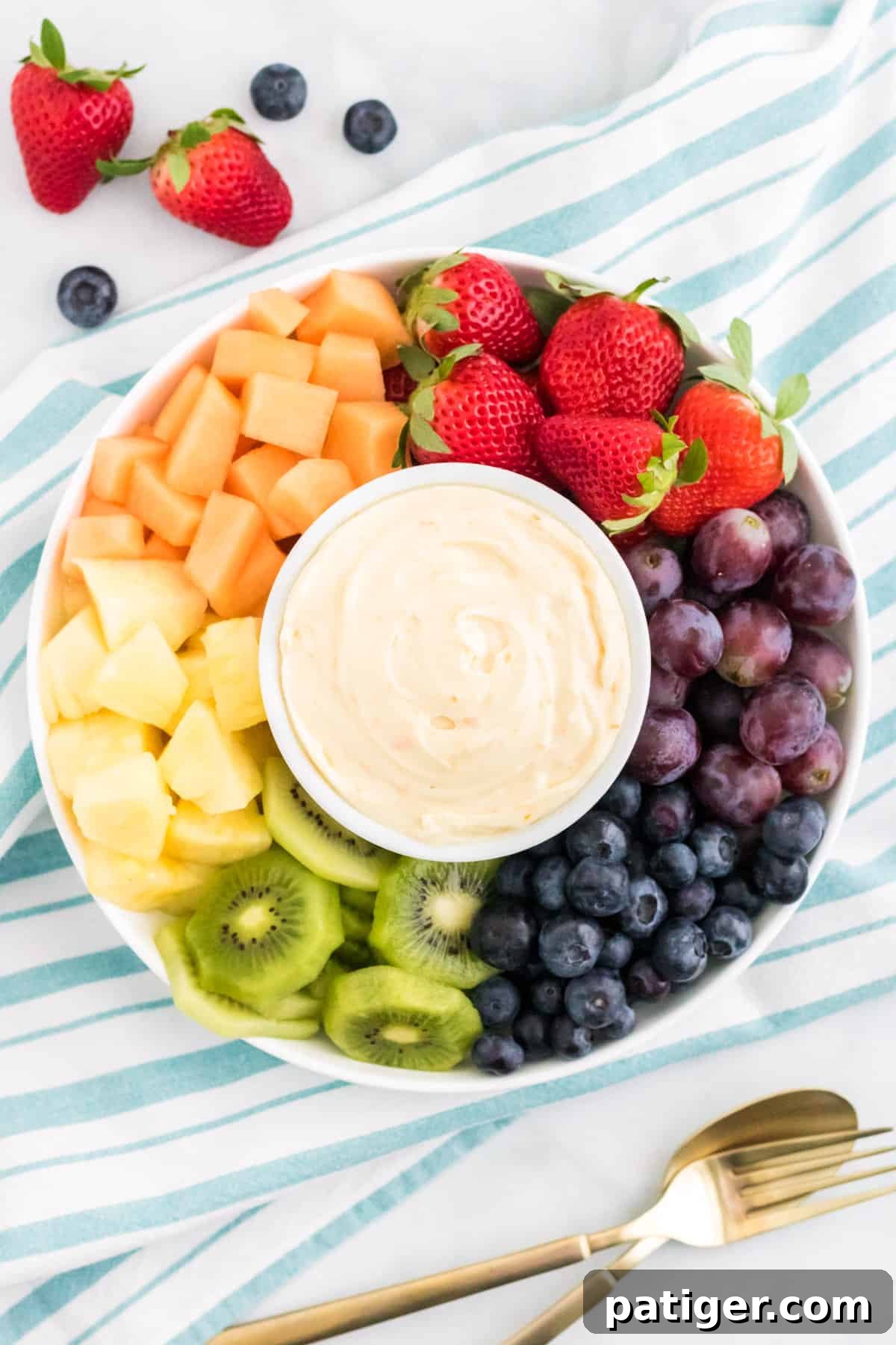 Cream cheese fruit dip on a platter surrounded by fresh fruit.