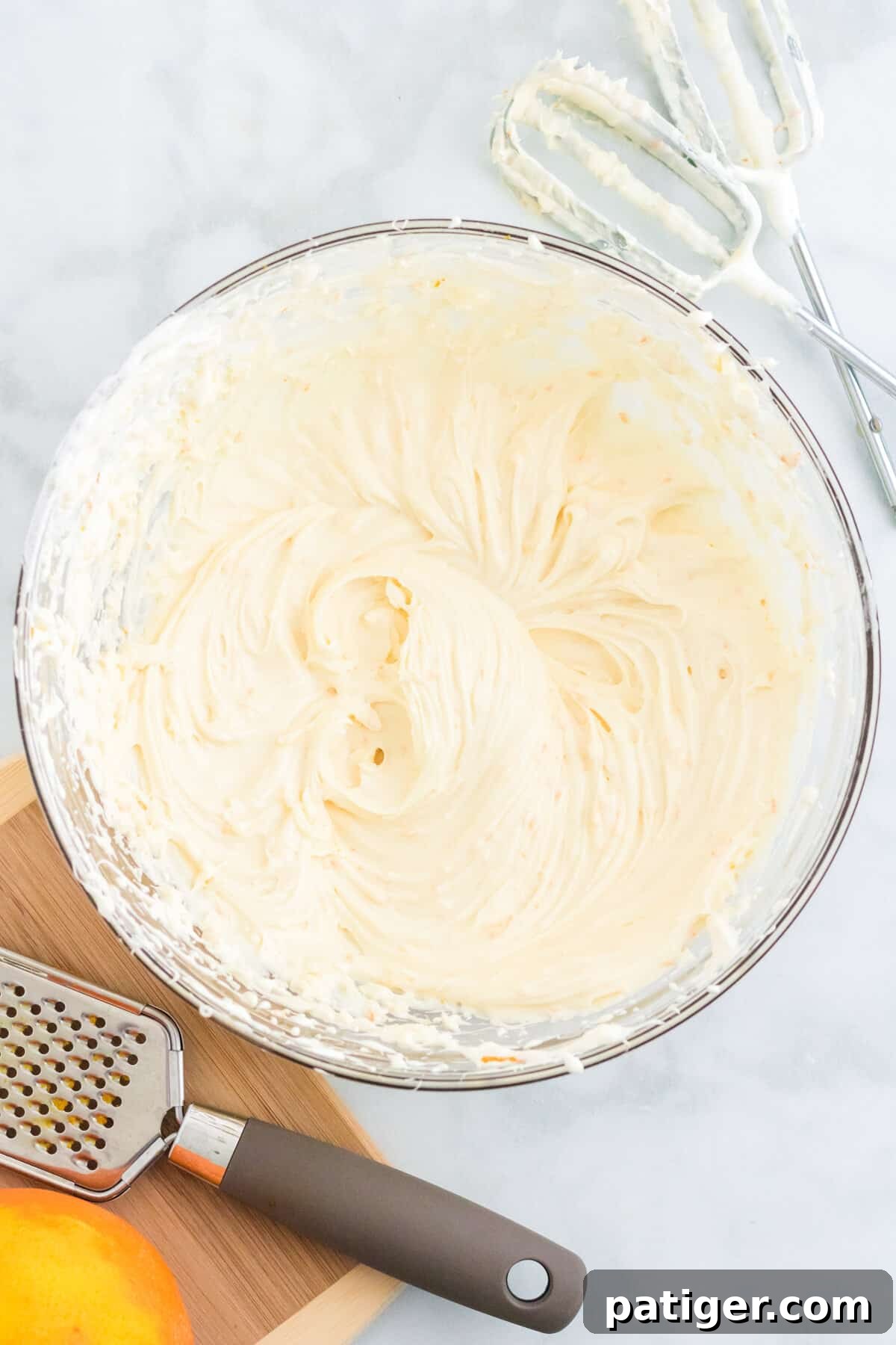 Large glass bowl with whipped cream cheese fruit dip. Hand mixer beater attachments are next to the bowl.