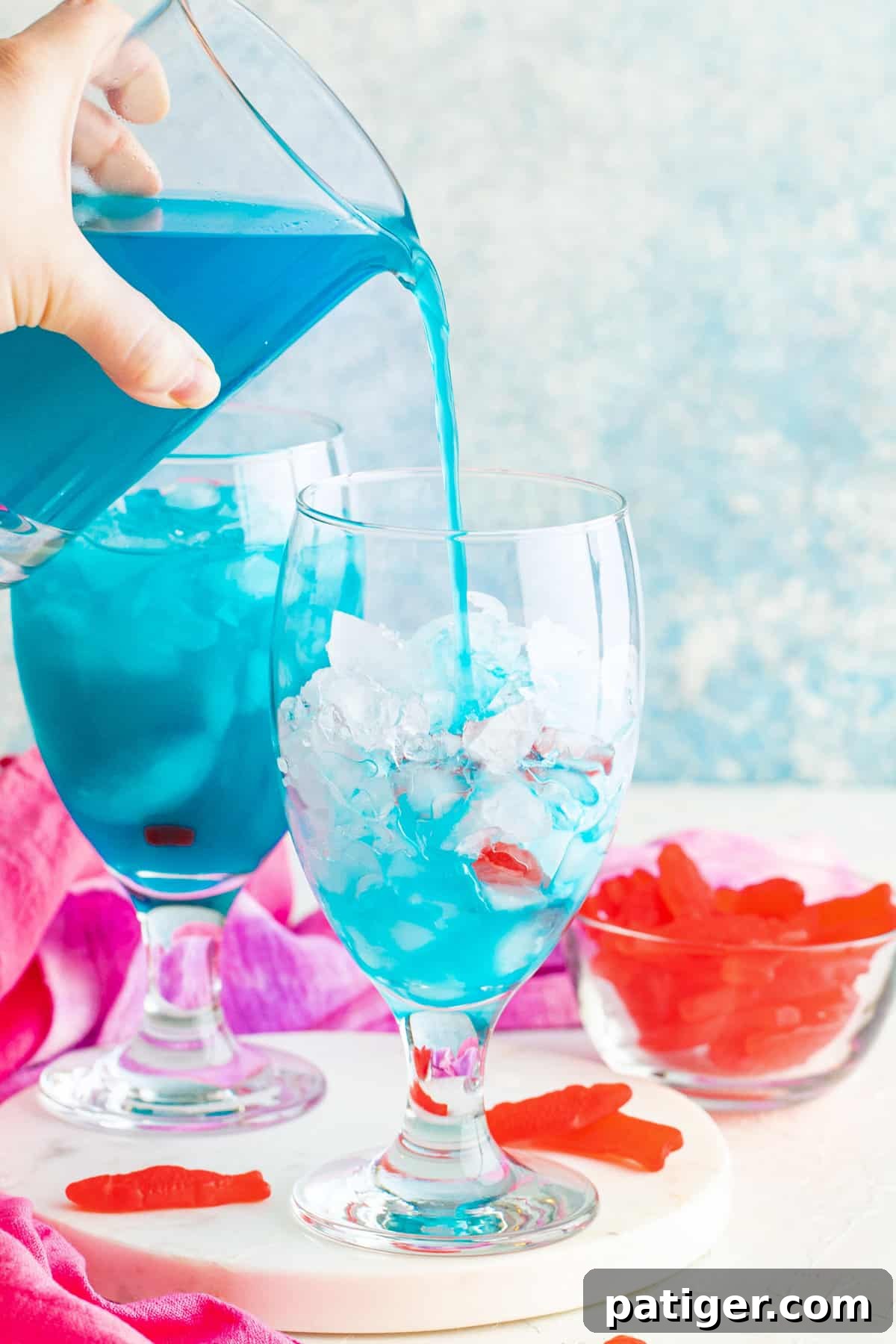 Pouring blue drink into cocktail glass.