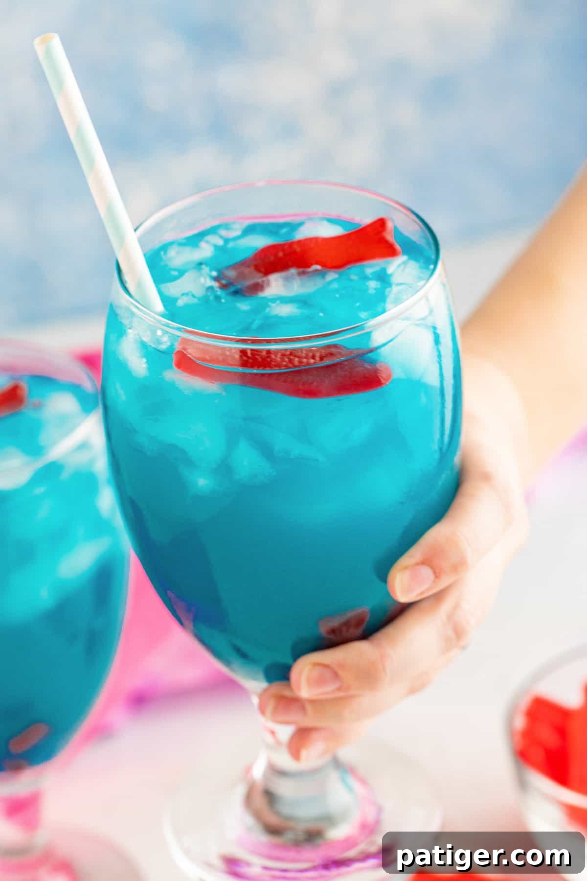 Hand holding ocean water cocktail with swedish fish.