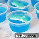 Shark jello shot with blue gelatin and shark gummy candy on top.