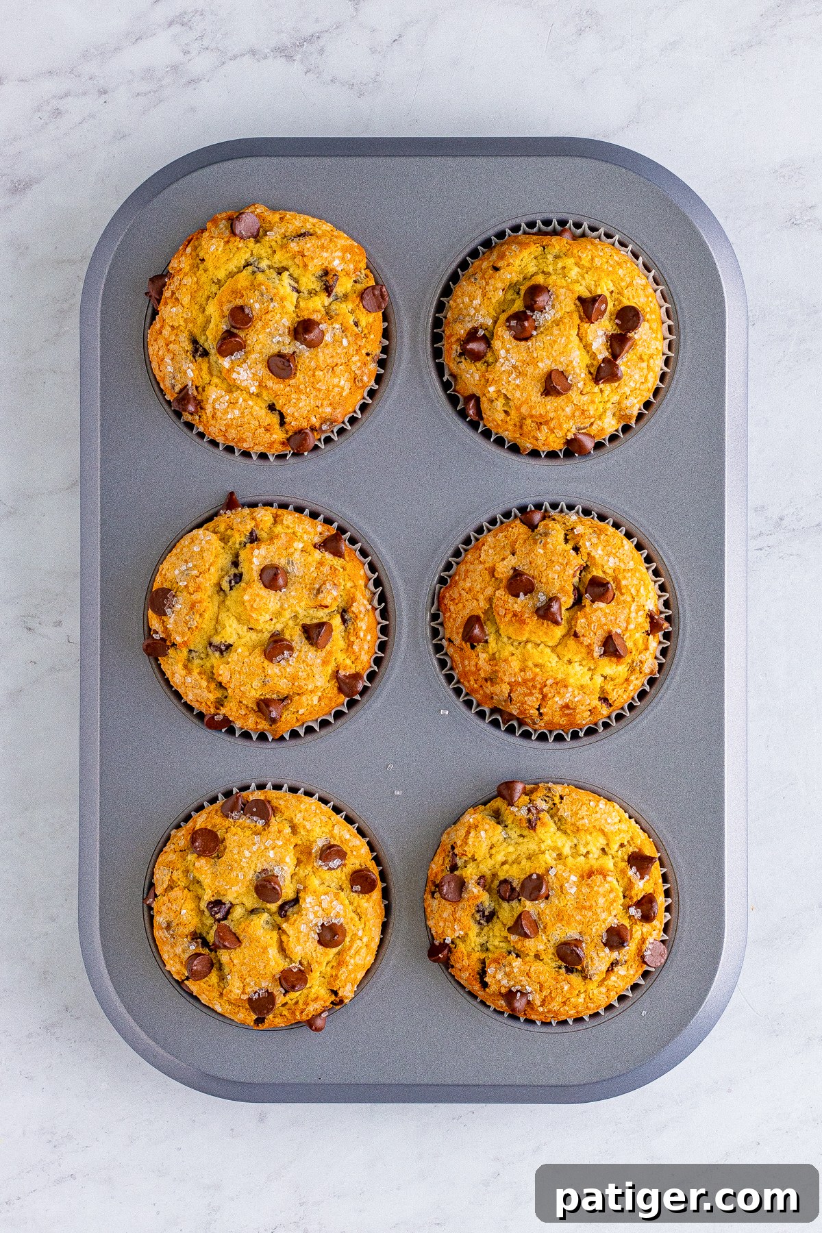 Ultimate Bakery Chocolate Chip Muffins 11 Freshly baked homemade chocolate chip muffins still in the jumbo muffin tin, showcasing their golden-brown, domed tops.