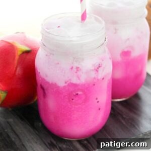 Copycat Starbucks Dragon Drink with vibrant pink mango dragonfruit refresher drink in mason jar topped with coconut milk.