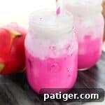 Copycat Starbucks Dragon Drink with vibrant pink mango dragonfruit refresher drink in mason jar topped with coconut milk.