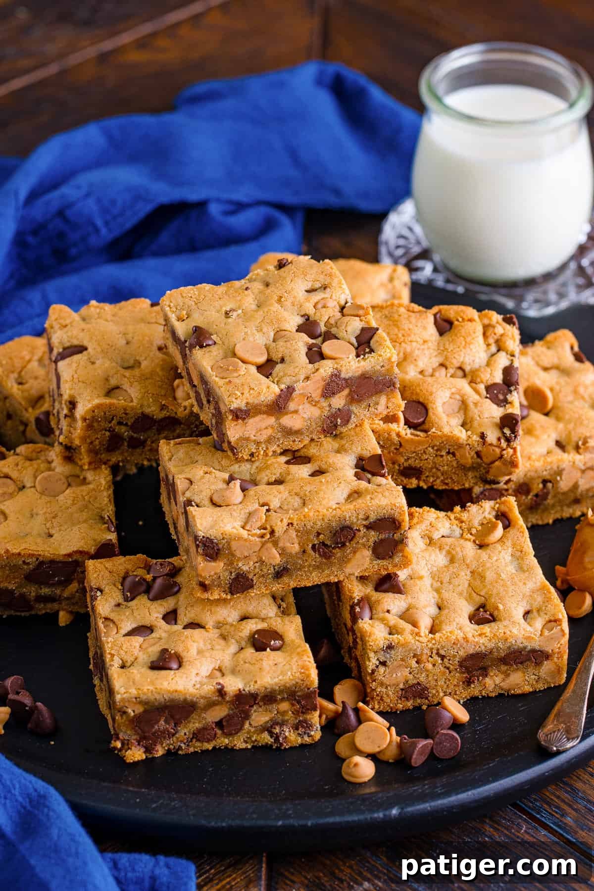 Peanut Butter Chocolate Chip Indulgence Bars 2 Peanut butter chocolate chip cookie bars on black plate with glass of milk.