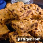 Peanut butter chocolate chip cookie bars piled on a plate.