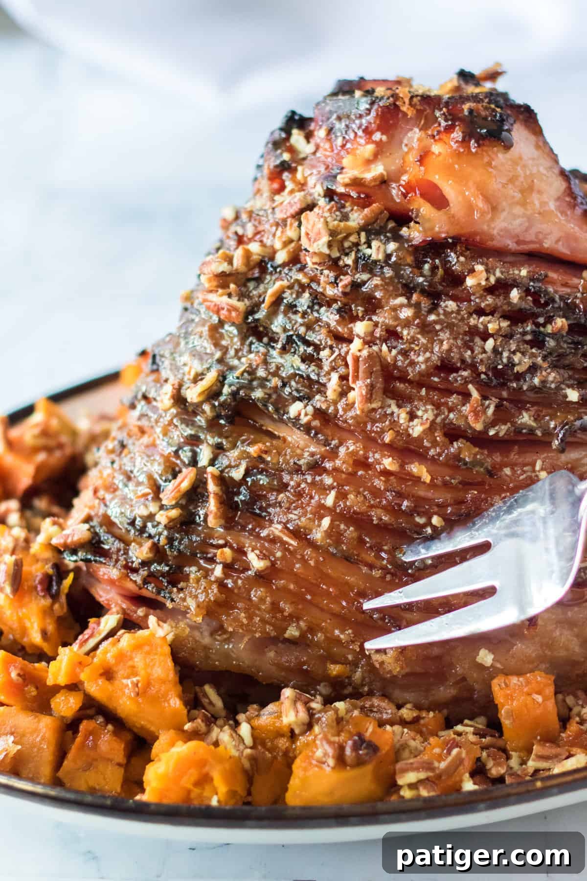 Spiral cut pecan glazed ham with chopped sweet potatoes, ready to serve.