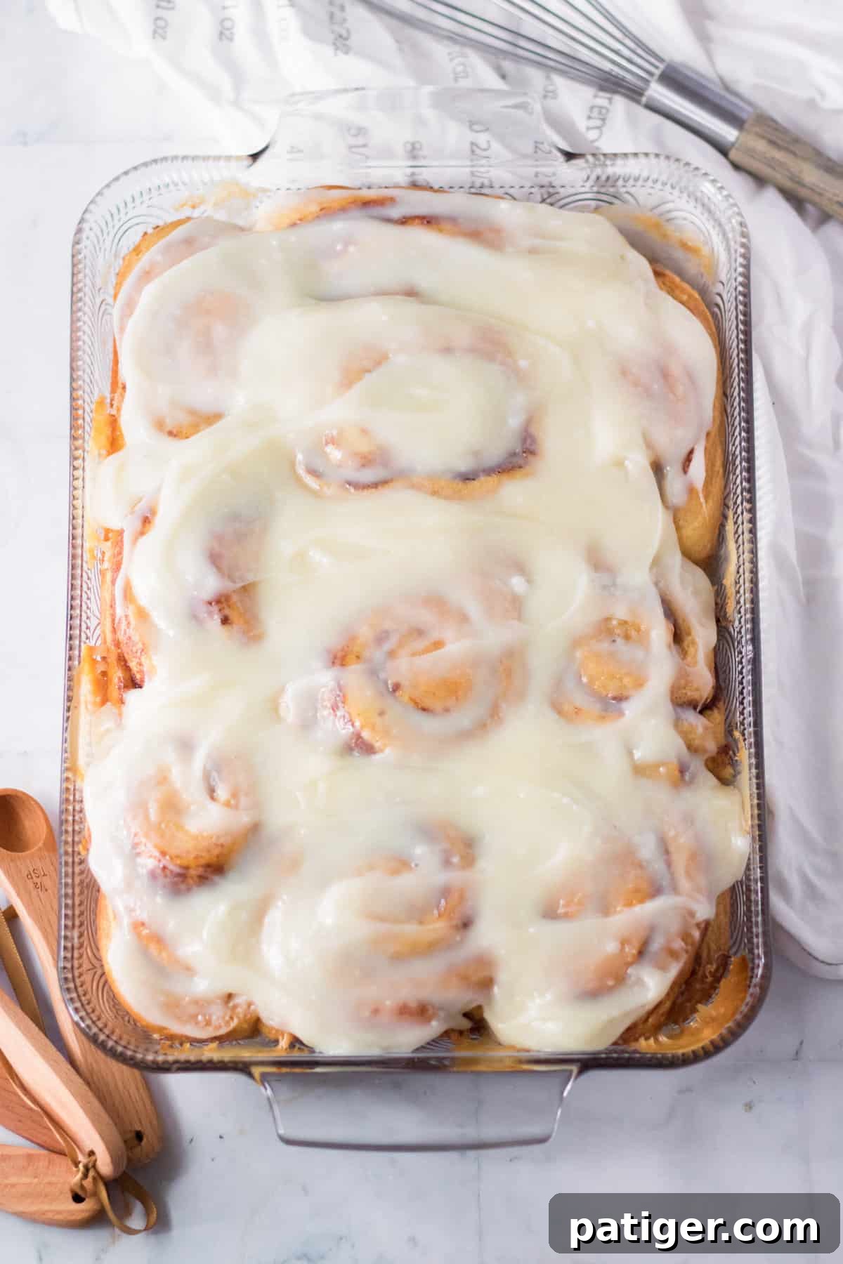 Cinnamon rolls with cream cheese frosting in a glass casserole dish.