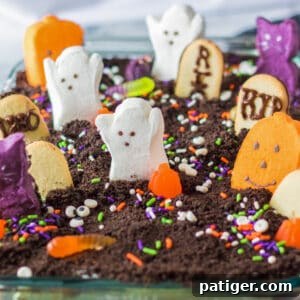Ghosts in the Graveyard Dessert topped with peeps ghosts, cookie tombstonea, and other Halloween candy.