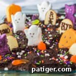 Haunted Cemetery Poke Cake 13 Ghosts in the Graveyard Dessert topped with peeps ghosts, cookie tombstonea, and other Halloween candy.