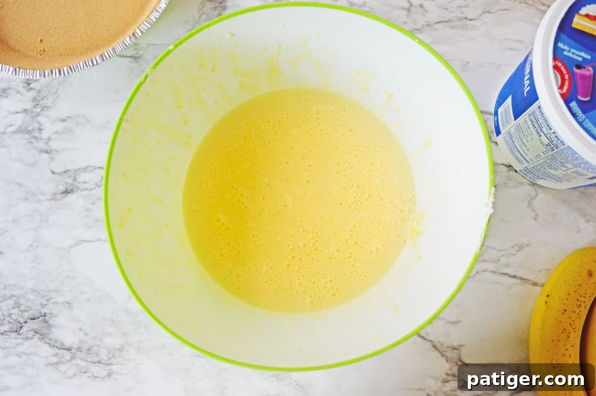 Smooth mixture of cream cheese and pudding in a large mixing bowl, ready for the next step.