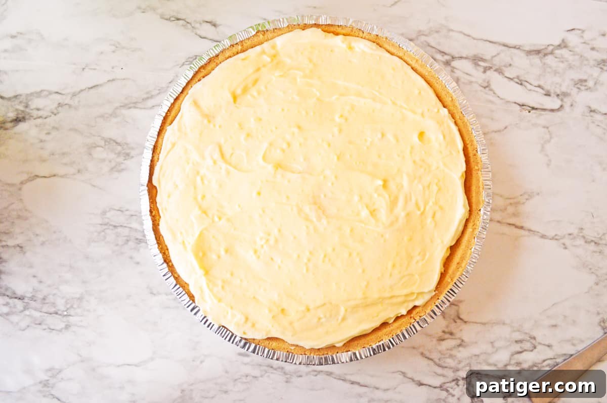 The creamy banana cream pudding filling neatly spread into a pre-made graham cracker crust.