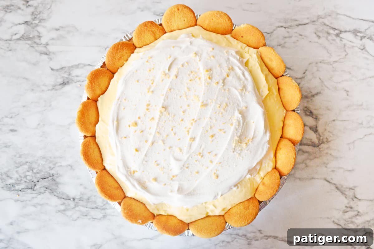 The finished banana pie, beautifully topped with generous whipped topping and sprinkled Nilla wafer crumbles, ready to serve.