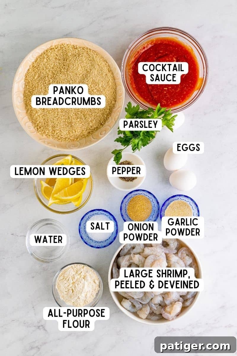 All the fresh ingredients laid out on a table for making panko shrimp, including raw shrimp, flour, spices, eggs, panko breadcrumbs, parsley, and lemons.
