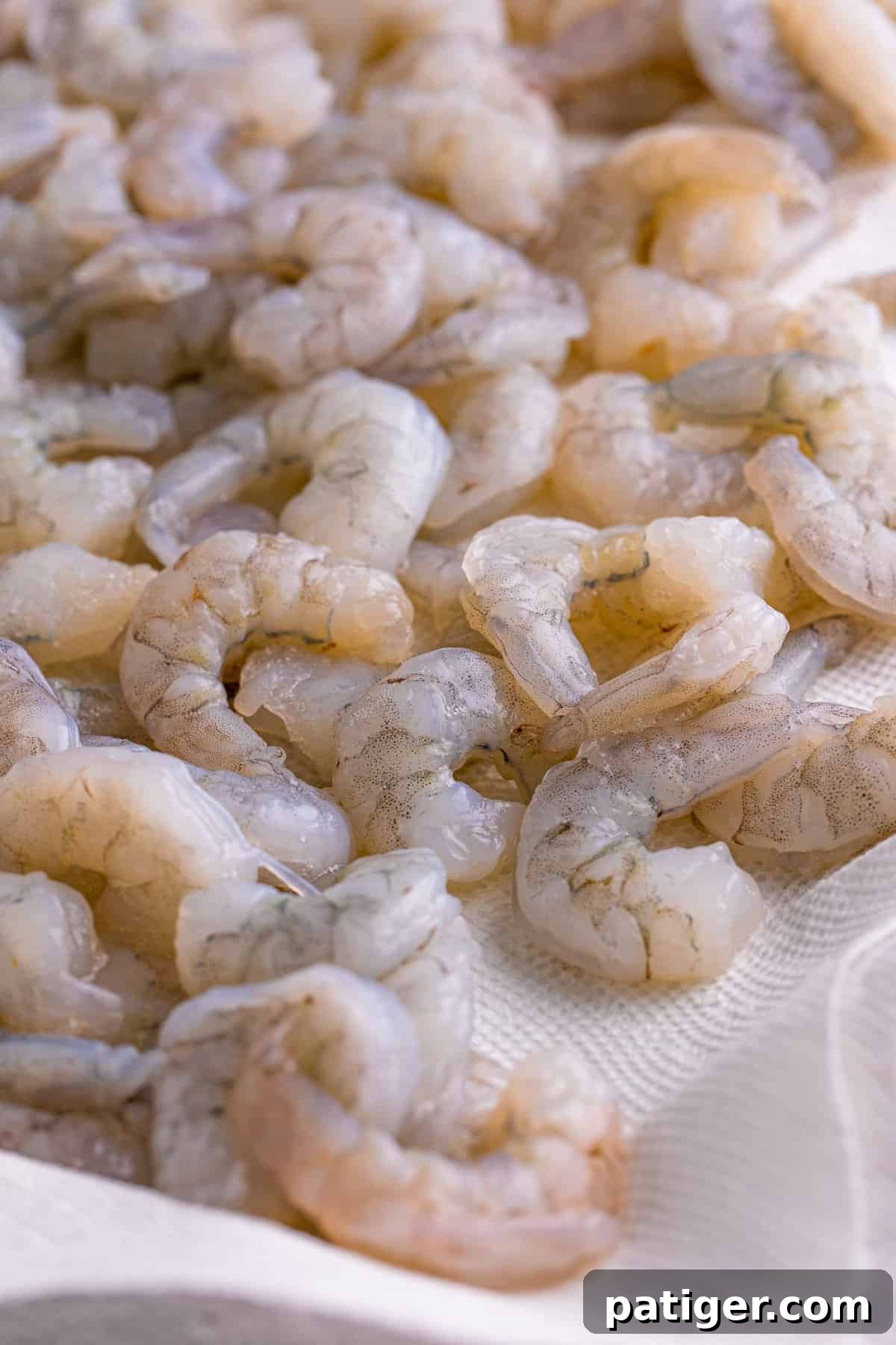 Raw, deveined shrimp laid out on a paper towel, patted dry and ready for seasoning.