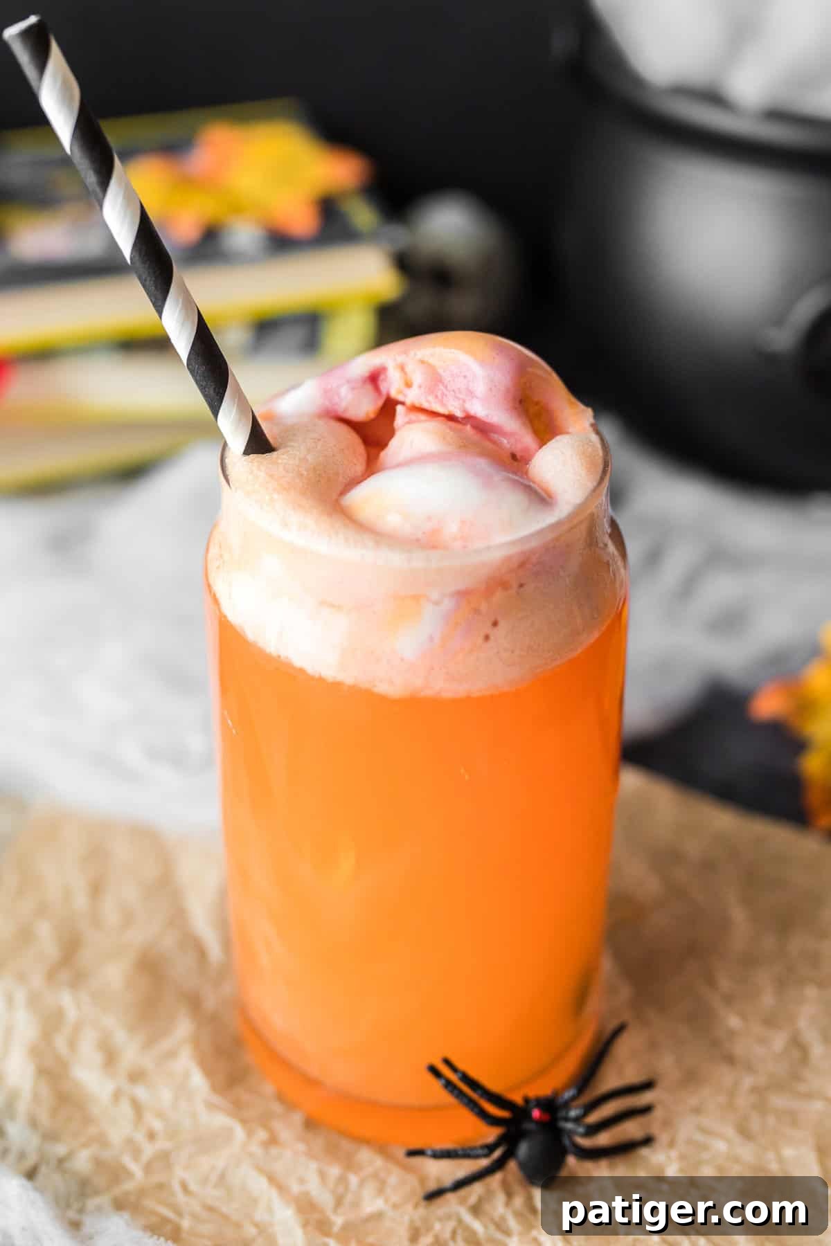 Whimsical Concoction 6 Orange hocus pocus punch for kids in glass with black and white straw.