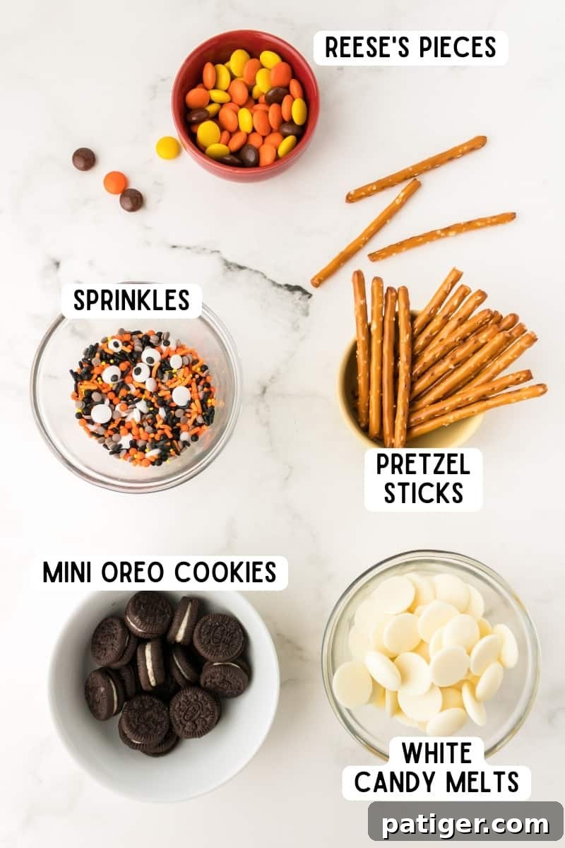 Ingredients for halloween bark recipe: pretzels sticks, reese's pieces, white candy melts, mini oreos.