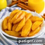 Copycat cracker barrel fried apples served on white plate with cinnamon sticks and juice next to them on the table.