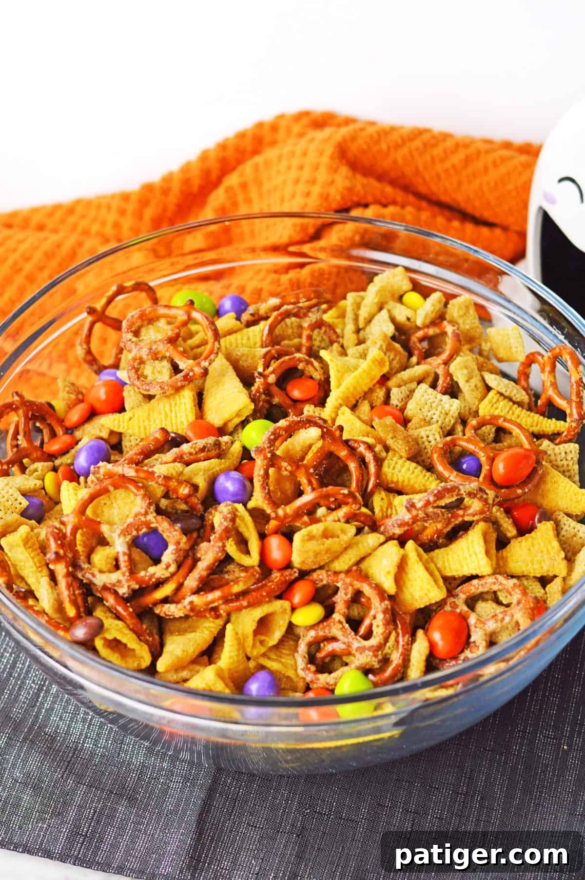 Monster Mash Snack Mix 2 Halloween chex mix in glass bowl with halloween decor.