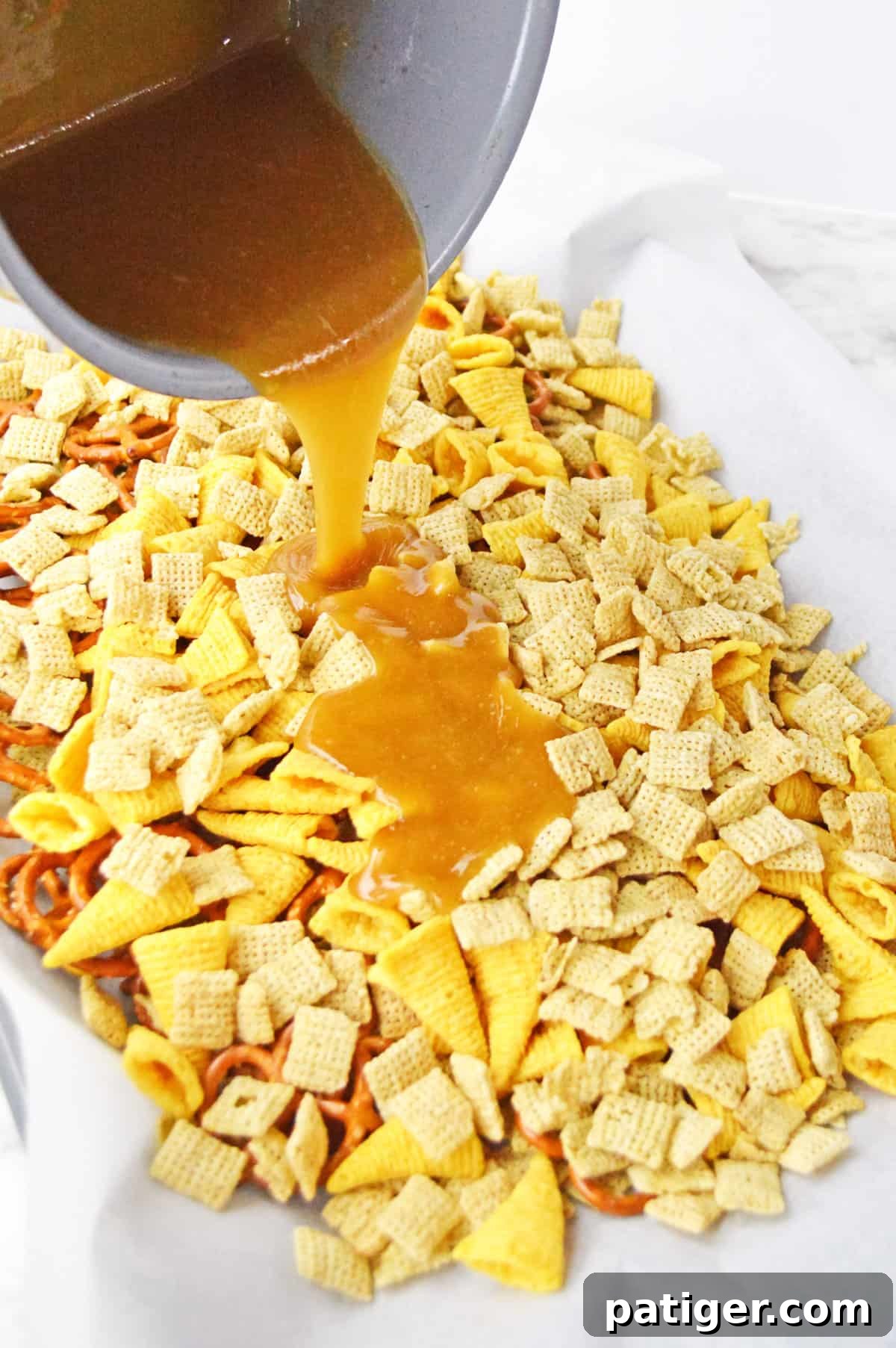 Monster Mash Snack Mix 6 Caramel sauce being poured out of pot and over chex mix on lined baking sheet.