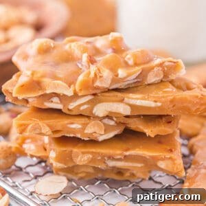 A beautiful stack of homemade nut brittle, showcasing its golden color, crisp texture, and generous chunks of almonds and peanuts.