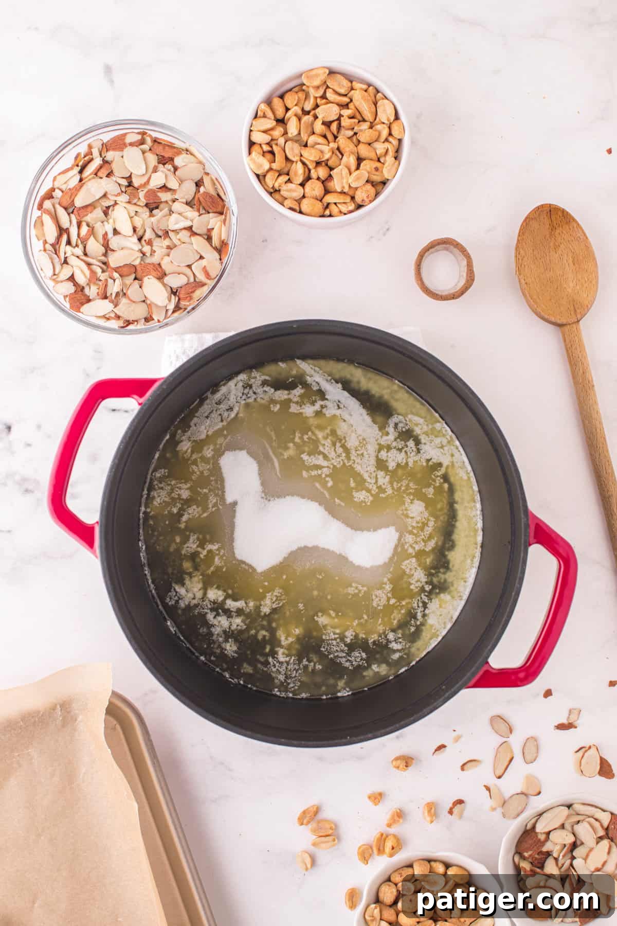 The sugar, light corn syrup, and water mixture being stirred in a large pot over heat after the butter has melted, forming a clear syrup.