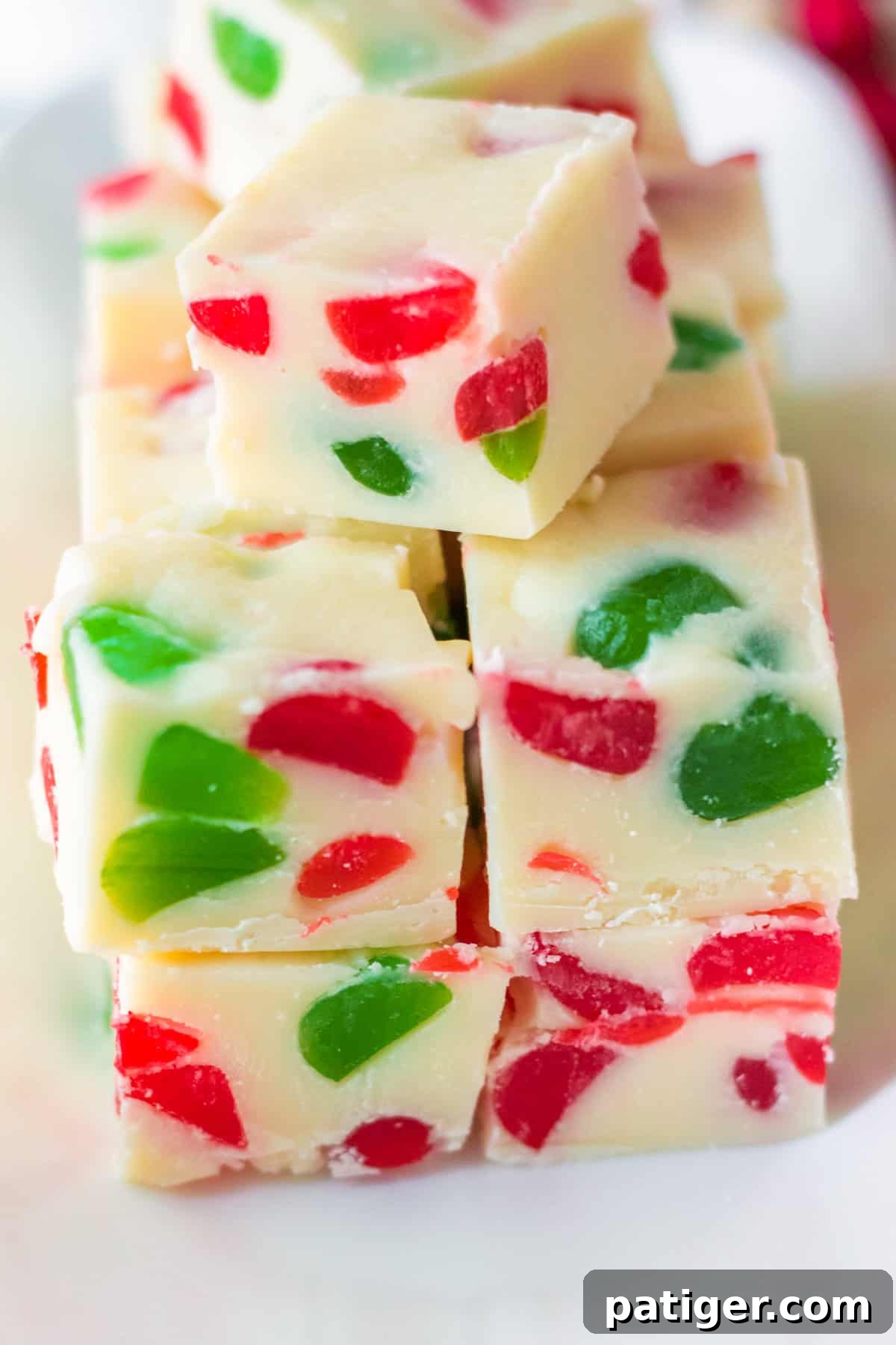 Close up of a pile of vanilla fudge with gumdrop candies, showing texture and color.