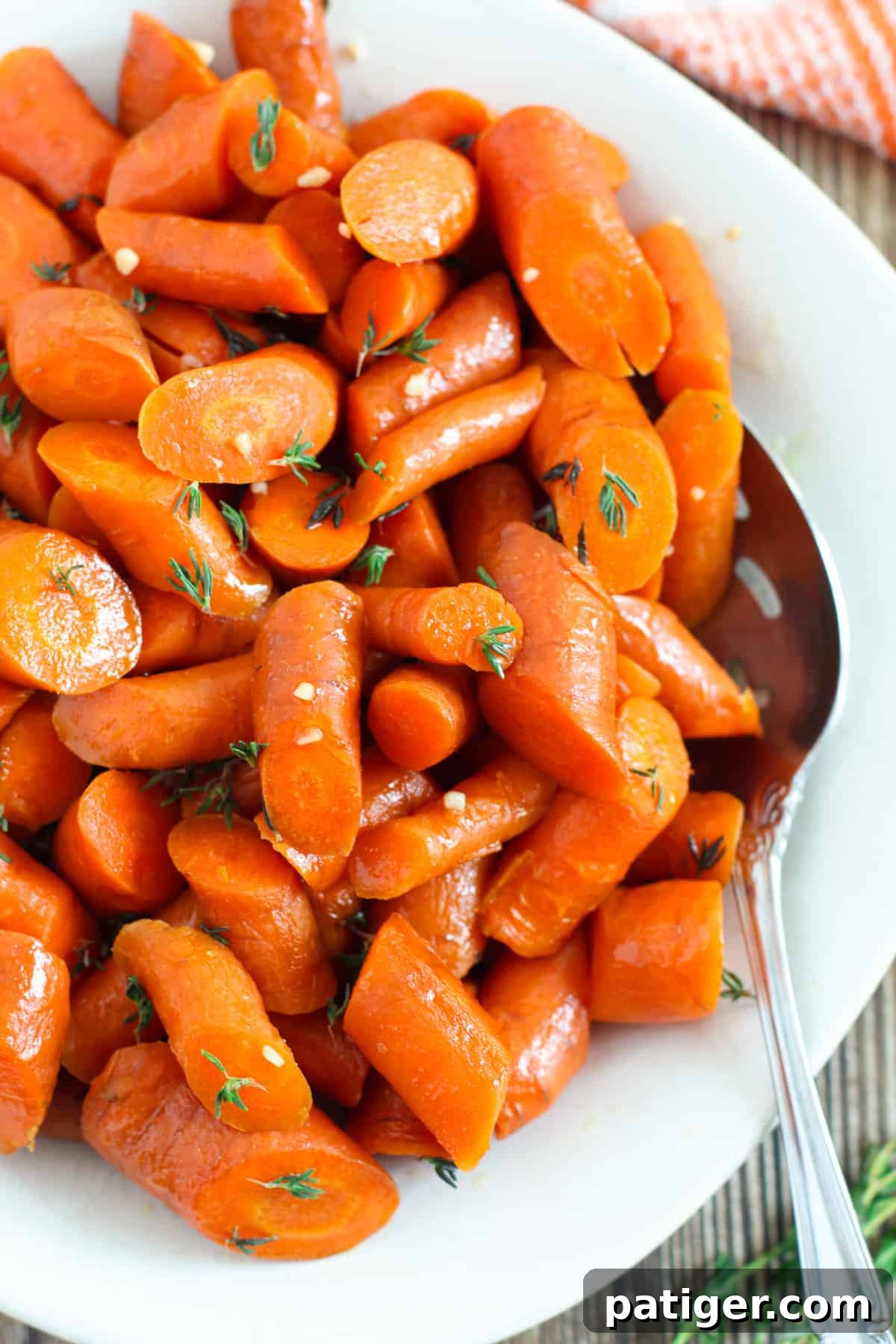 Slow cooker glazed carrots with a serving spoon, showcasing their rich brown sugar glaze and tender texture.