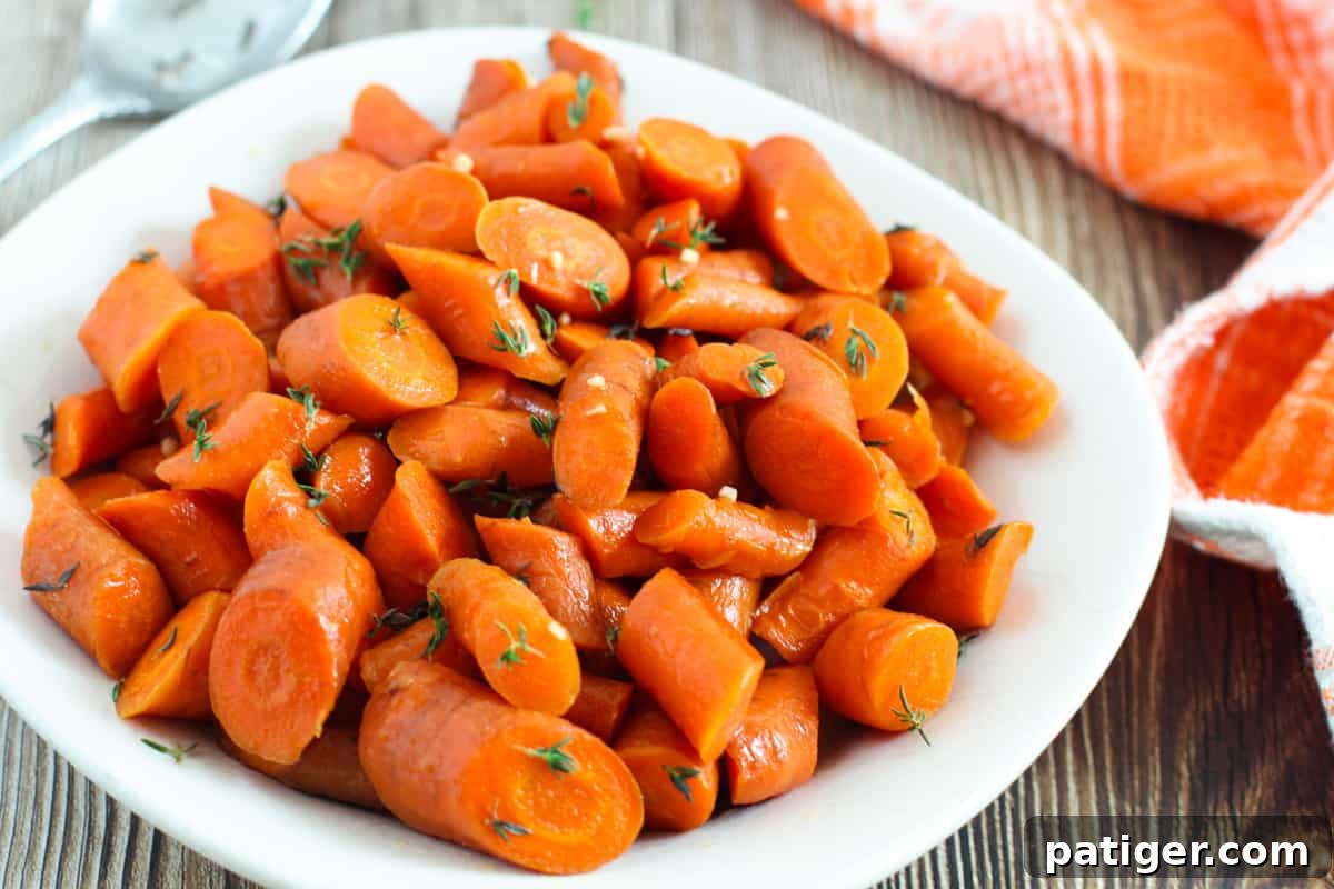 A serving of slow cooker glazed carrots on a pristine white plate, garnished with fresh herbs, ready to be enjoyed.