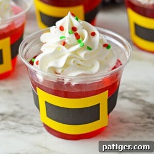 Santa jello cups with whipped cream and sprinkles, featuring Santa belt decorations.