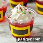 Santa jello cups with whipped cream and sprinkles, ready to be enjoyed.