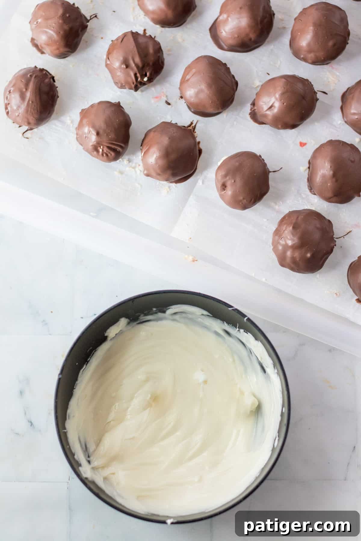 A bowl of melted white candy melts, ready for drizzling, next to a tray of chocolate-coated candies, adding a final elegant touch.