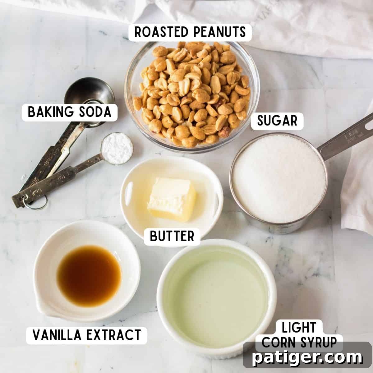 Instant Peanut Brittle 4 Neatly arranged ingredients for making microwave peanut brittle: a bowl of roasted peanuts, a bottle of vanilla extract, granulated sugar, a stick of butter, light corn syrup, and a small container of baking soda.