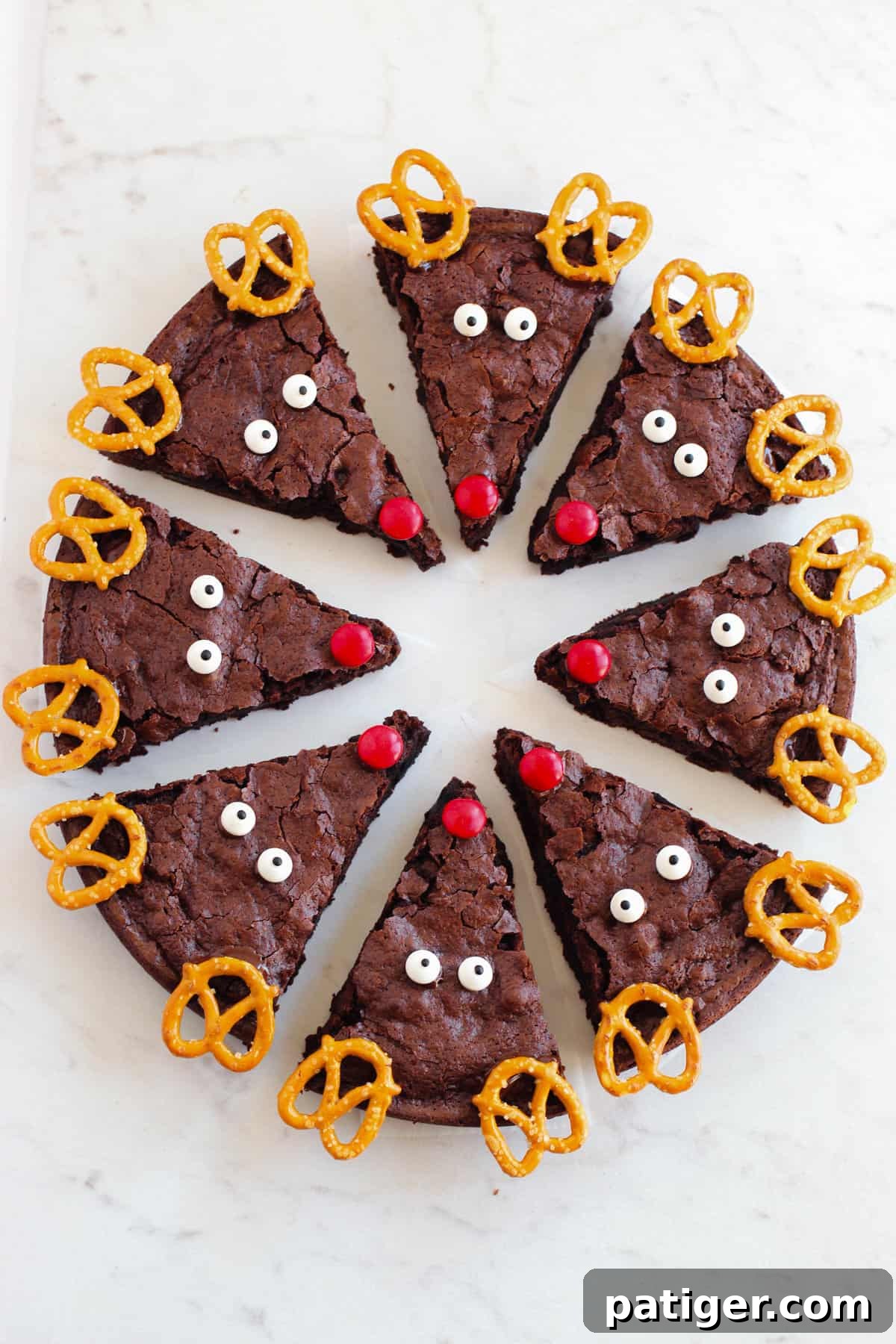 A round pan filled with freshly baked brownies, expertly sliced into triangular portions and individually decorated with cheerful reindeer faces, ready for holiday serving.