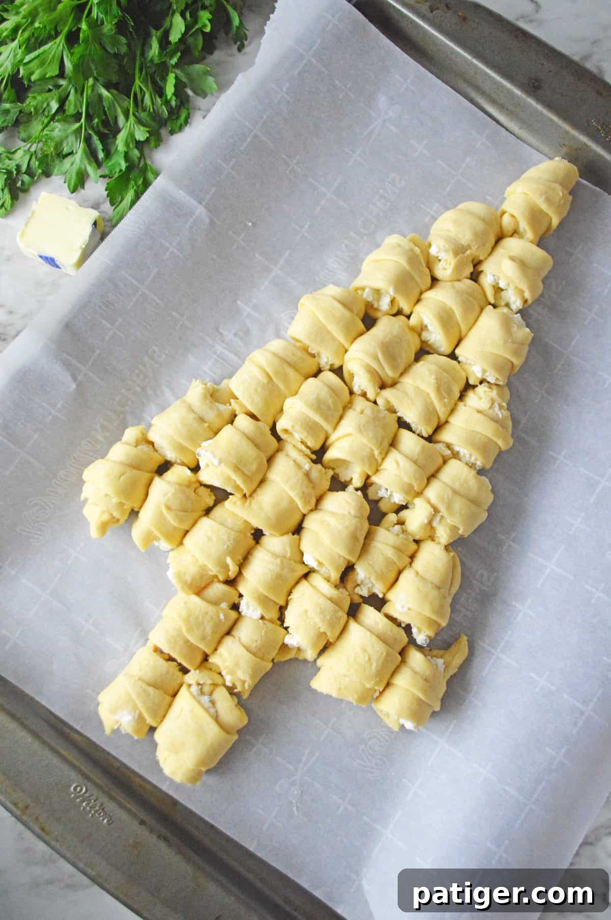 Rolled and cheese-filled crescents meticulously arranged on a lined baking sheet, forming a perfect Christmas Tree pattern, ready for the oven.
