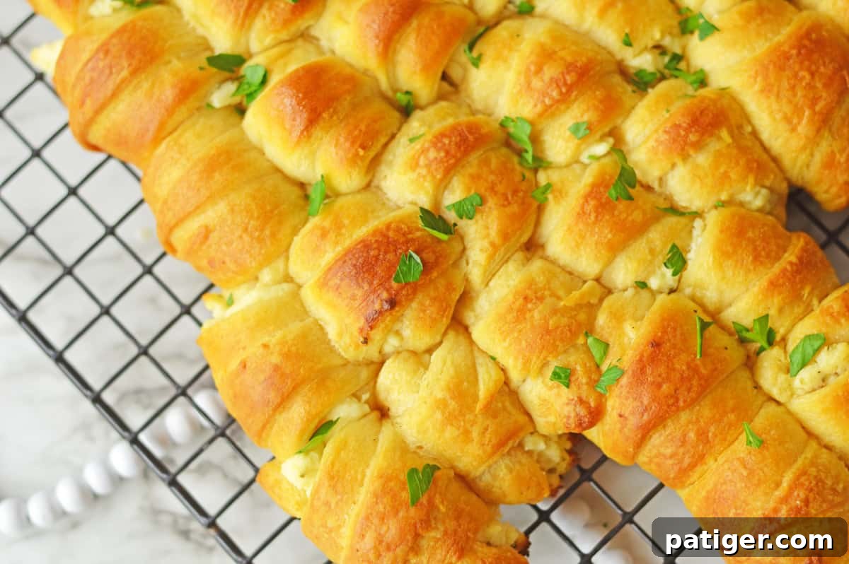Close-up of a perfectly baked pull-apart crescent Christmas tree, generously garnished with fresh parsley, presented on a wire rack.