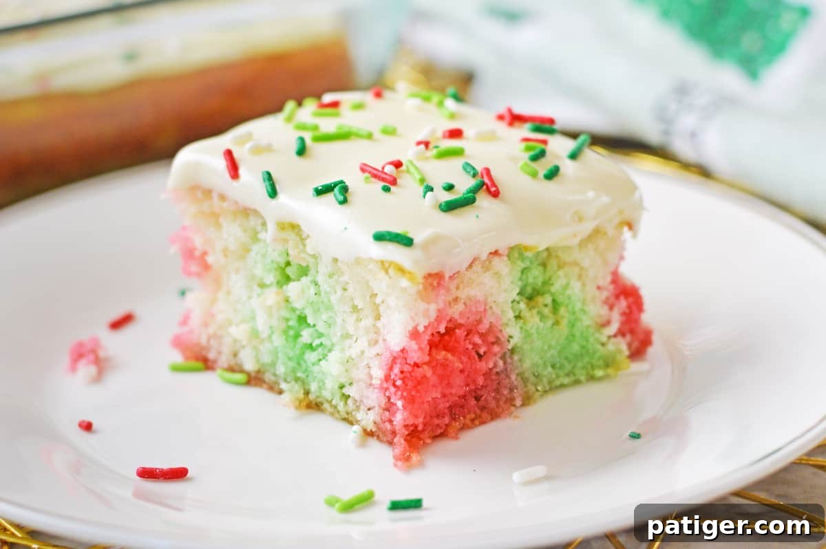 Square slice of jello poke cake with red and green jello injected throughout.