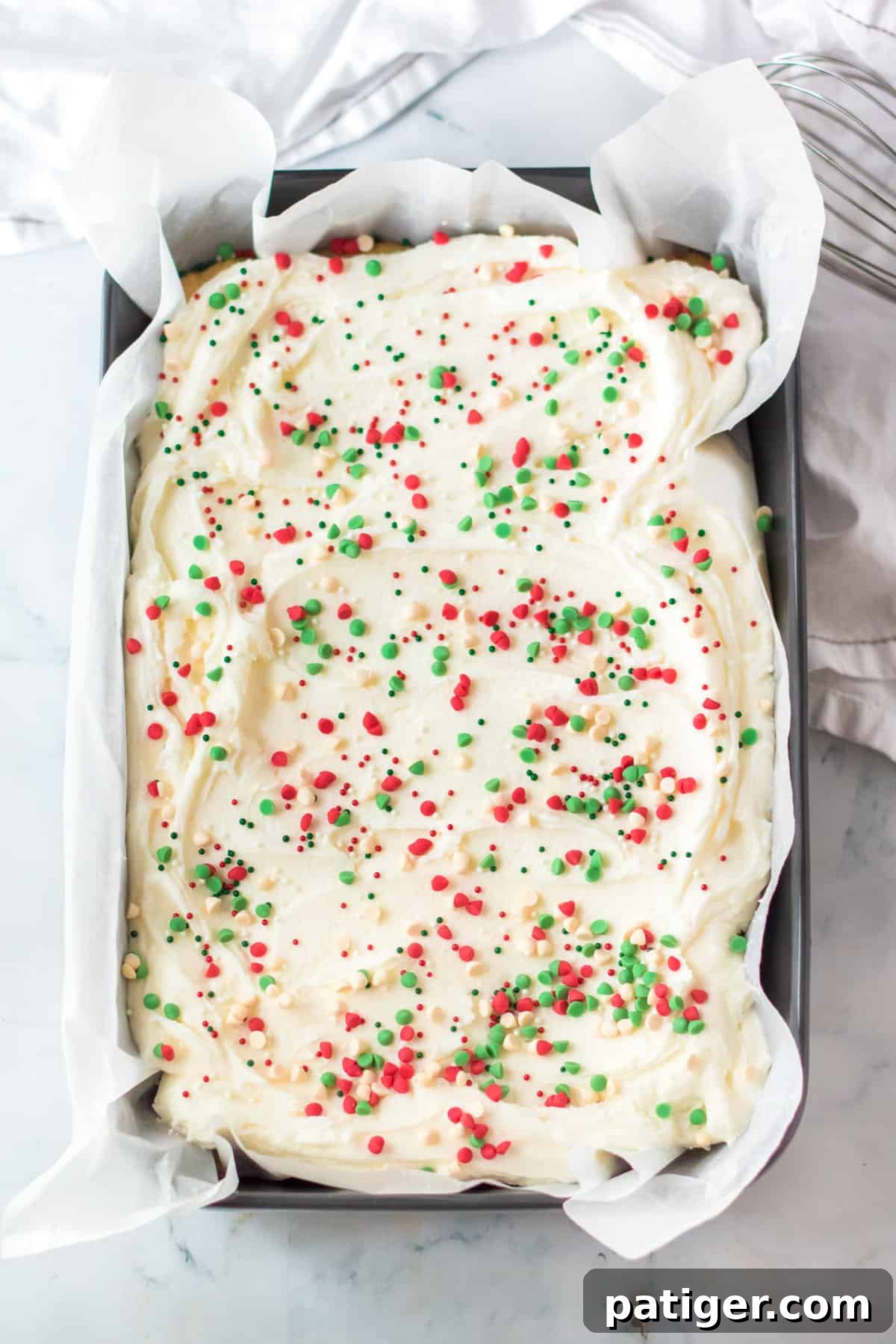 Pan of Holiday cookie bars topped with vanilla buttercream, holiday chips, and sprinkles.