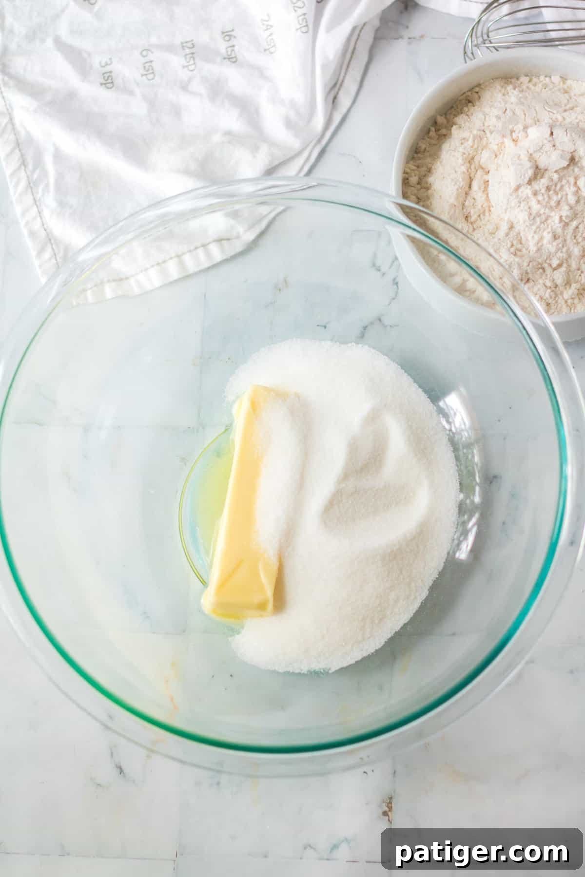 Butter and sugar in a glass mixing bowl.